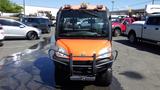 A 2013 Kubota RTV 1100 utility vehicle with an orange body and black grille is parked in a lot with visible dirt on the front tires