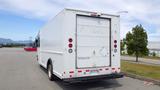 A white 2011 Ford Econoline delivery van with a rear loading door and red brake lights