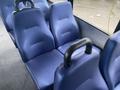 Blue vinyl seats inside a 2018 Chevrolet Express arranged in a row with two sets of seats and armrests visible