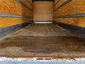 A 2022 Ford F-750 truck with an open cargo area featuring a wooden floor and metal ramp for loading and unloading materials