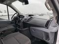 The interior of a 2017 Ford Transit showcasing the driver's seat dashboard and console with controls and storage compartments