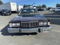 A 1982 Mercury Grand Marquis with a brown exterior and chrome accents is displayed from the front showcasing its distinctive grille and headlights