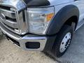 A 2013 Ford F-450 SD with chrome grille and headlights visible from the front angle showcasing the tire and fender design