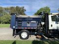 A blue 2007 International 7300 dump truck with a raised bed for unloading debris and equipment attached for loading and unloading materials