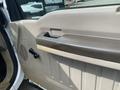 Interior door panel of a 2010 Ford F-550 featuring a handle control and speaker grille in light beige and brown colors