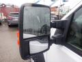 Close-up of the side mirror of a 2009 Ford F-450 SD featuring dual mirrors and a wet surface with raindrops