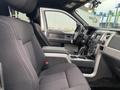 Interior view of a 2014 Ford F-150 with black cloth seats and a console between the front seats showcasing the dashboard and controls