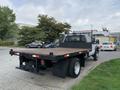 A 2012 Ford F-550 flatbed truck parked with a wooden bed and a metal mesh tailgate in the foreground