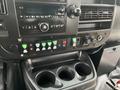 The interior dashboard of a 2018 Chevrolet Express featuring various control buttons and a stereo system with cup holders underneath