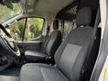 A 2023 Ford Transit interior showcasing two black fabric seats with a patterned design and a divider separating the front from the cargo area