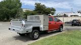 A red 2013 RAM 2500 pickup truck with a silver service body and toolboxes mounted in the truck bed