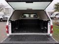 A 2018 Ford F-150 truck bed with a camper shell open displaying a clean, lined interior and no visible cargo