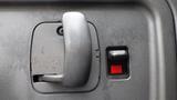 Close-up of a door handle and lock mechanism in a 2008 Chevrolet C7500 showing a gray handle and a red unlock button