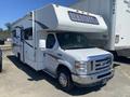 A white 2012 Ford Econoline camper van with a raised roof and large front windshield showcasing a streamlined design and chrome accents