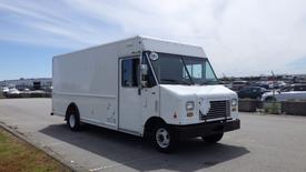 A white 2011 Ford Econoline cargo van with a boxy shape and large front windows parked on a paved surface