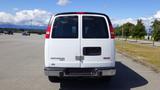 A white 2015 GMC Savana van with a rear double door and a black grill located at the back