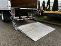 A 2022 Ford F-750 with a foldable aluminum loading ramp extended at the rear of the truck