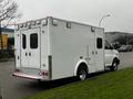 A white 2016 Chevrolet Express van with an enclosed back and multiple rear lights is parked on the street