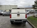 A white 2018 Chevrolet Colorado with a bed cover viewed from the rear showcasing its tailgate and emblem