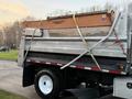 A 2006 Freightliner M2 106 truck with a silver and orange dump body secured with straps