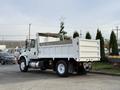 A white 2015 International DuraStar 4300 dump truck with a flatbed and an open cargo area parked on a lot