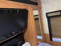 Interior view of a Newmar Canyon Star 36 Foot Class A Motorhome featuring a flat-screen television and a mirror against a wood-paneled wall