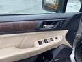 Interior view of a 2019 Subaru Outback driver's side door with controls for windows and locks featuring beige upholstery and wooden accents