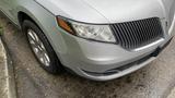 A silver 2013 Lincoln MKT parked with rain droplets on its surface showcasing its distinctive grille and sleek design