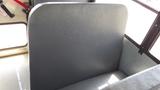 A gray bus seat with a high back resting against the interior wall of a bus