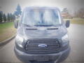 A black 2015 Ford Transit van with a prominent front grille and headlights visible