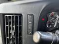 Close-up of the control panel in a 2015 Chevrolet Express featuring buttons for headlights, a warning light, and a check mark switch