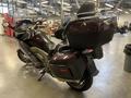 A 2013 BMW K1600GTL motorcycle with a dark brown finish featuring a large rear trunk and distinctive body design