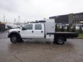 A white 2009 Ford F-450 SD with a flatbed and utility box on the back is parked in a lot