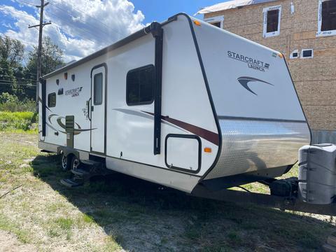 A white 2014 Launch 24RLS camper trailer with a curved front and side graphics parked on a grassy area