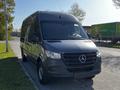 A 2021 Mercedes-Benz Sprinter van in dark gray color parked with a sleek front design and prominent Mercedes-Benz emblem on the grille