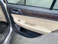 A 2019 Subaru Outback door interior featuring beige leather upholstery a wooden trim and a control panel for the windows and locks