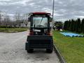 A 2018 Kubota B2650 tractor viewed from the rear showing its enclosed cab and rear attachment with a red and black color scheme