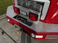 The rear view of a red 1994 Freightliner FL80 showing its polished metal bumper tail lights and a winch mounted on a diamond plate surface