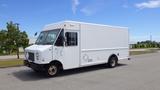 A white 2011 Ford Econoline van with a boxy design and large side windows parked on a paved surface