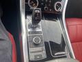 Interior console of a 2020 Land Rover Range Rover Sport featuring gear selector buttons and control dials on a glossy surface with red leather seats