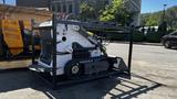 A 2024 Power JQ 400 compact track loader with a white and black exterior is displayed on a metal frame with a front loader attachment