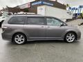 A 2013 Toyota Sienna in gray parked with its side view visible showcasing its sleek design and alloy wheels