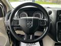 A 2011 Dodge Grand Caravan steering wheel with the Dodge logo and control buttons visible