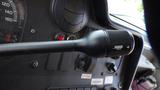 A close-up of the turn signal lever in a 2011 Ford Econoline featuring a black plastic design and various controls in the background