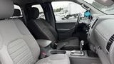 Interior of a 2016 Nissan Frontier featuring two bucket seats with fabric upholstery and a center console with gear shift and cup holders