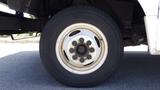 Close-up of a 2011 Ford Econoline tire and wheel showing the white rim and black tire with distinct tread pattern