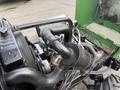 A close-up view of the engine and exhaust system of a 1994 John Deere F1145 featuring various mechanical components including pipes and a cylindrical filter