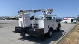 A 2011 Ford F-450 SD with a utility body and a bucket lift attached at the rear used for aerial work