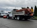 A 2009 Ford F-550 truck with a silver flatbed and an orange plow attached in the front