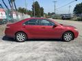 A red 2007 Toyota Camry Hybrid parked on gravel with its side view visible